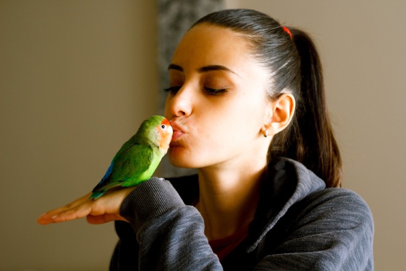 young girl kissing her pet lovebird Dusan Stevic Shutterstock